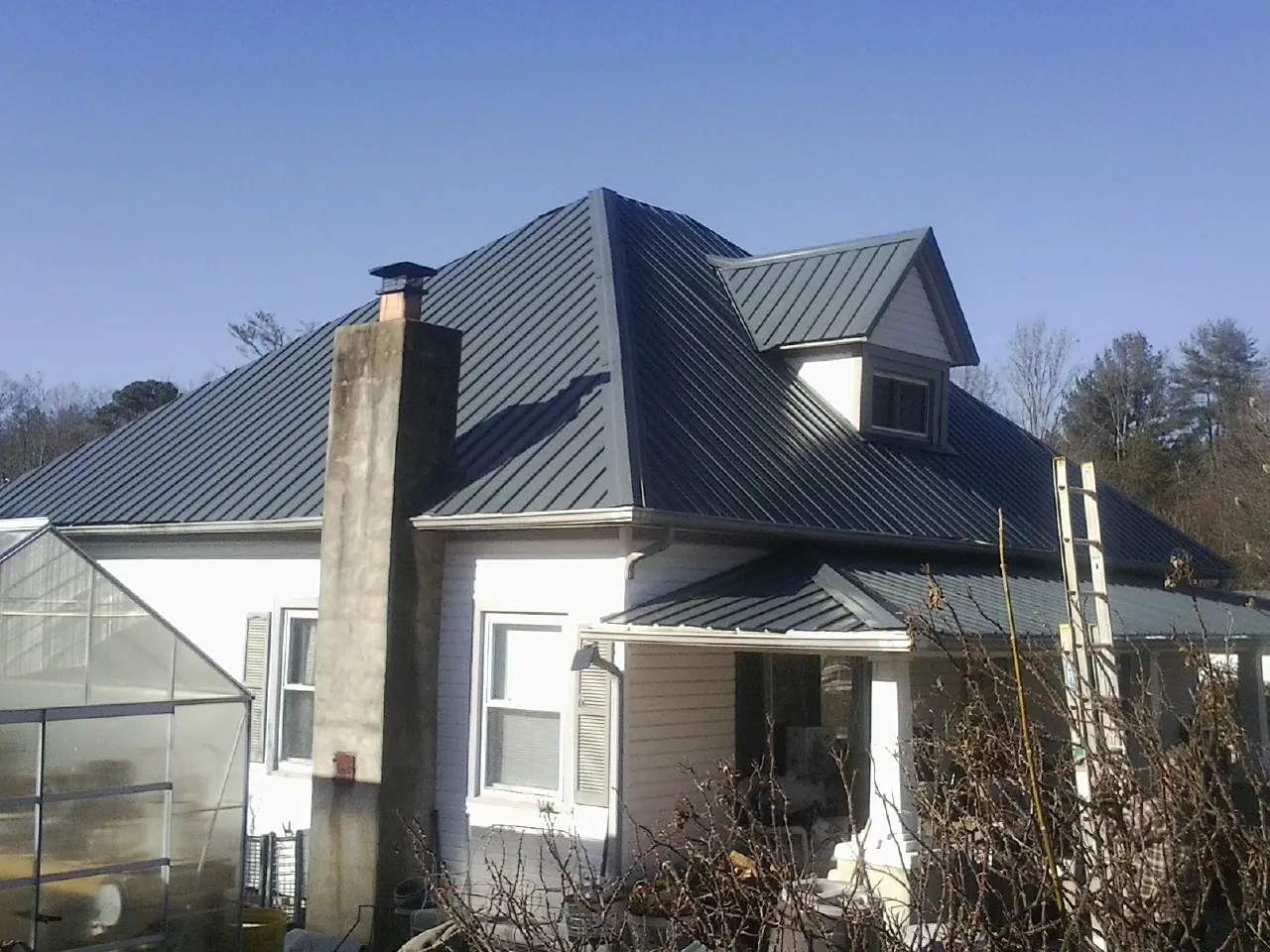 Dark blue standing seam metal roof on a white farmhouse with dormer — Slate & Tile Roof Repair by Roofing Brothers in Shermans Dale