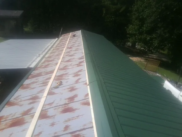 Old rusted panels beside newly installed green metal roofing — Wind Damage Roof Repair by Roofing Brothers in Shermans Dale