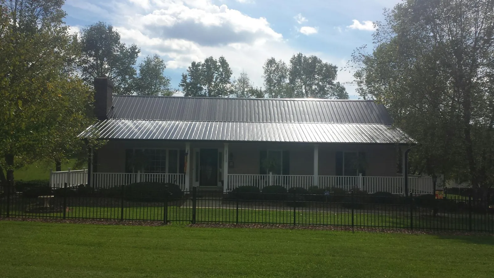 Gray metal roof on a brick ranch with a full width front porch — Gutter Guard Installation work by our crew in Shermans Dale