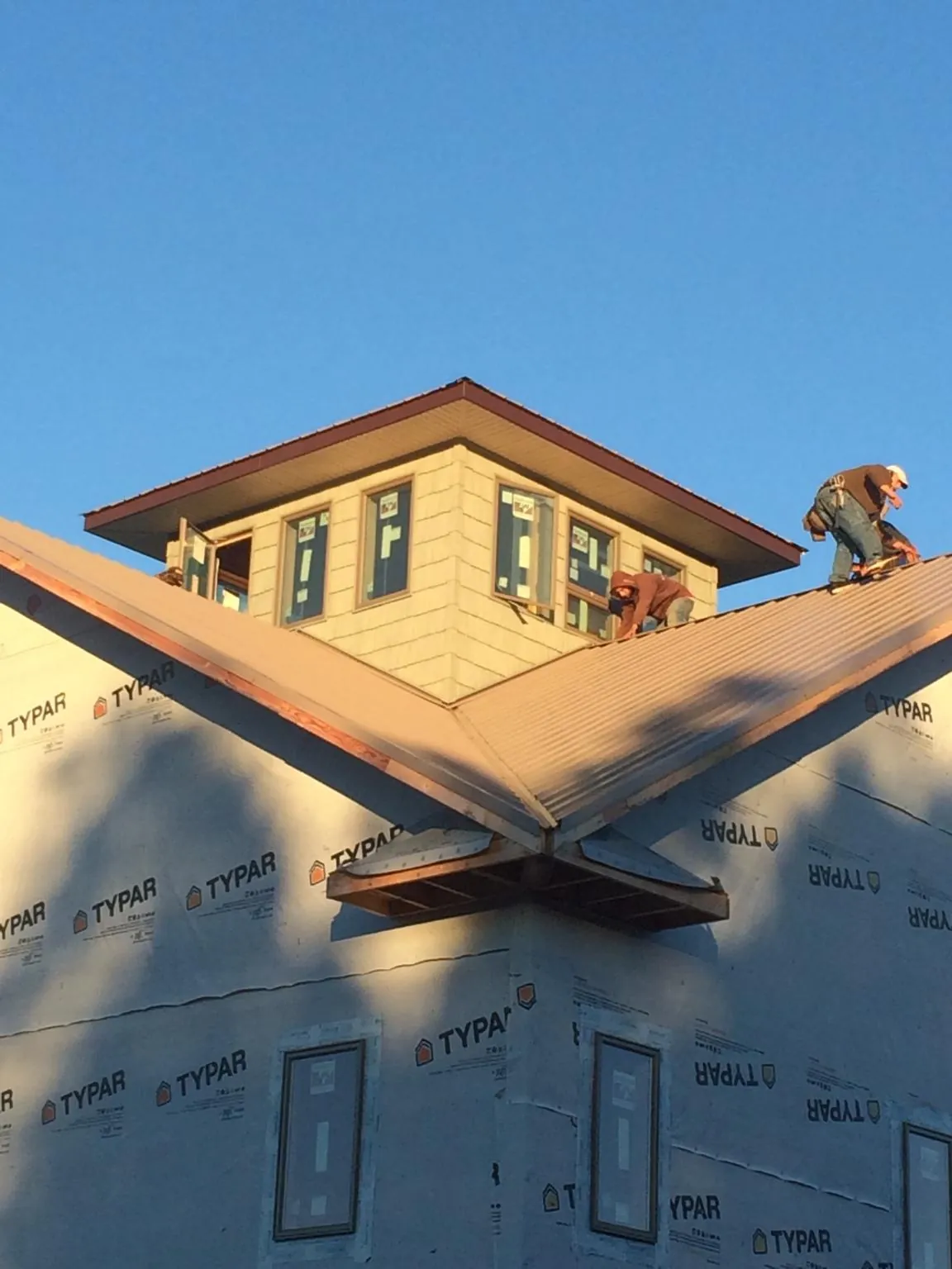 Roofers working around a rooftop cupola on a new metal roof at sunset — Roof Waterproofing in Shermans Dale by Roofing Brothers